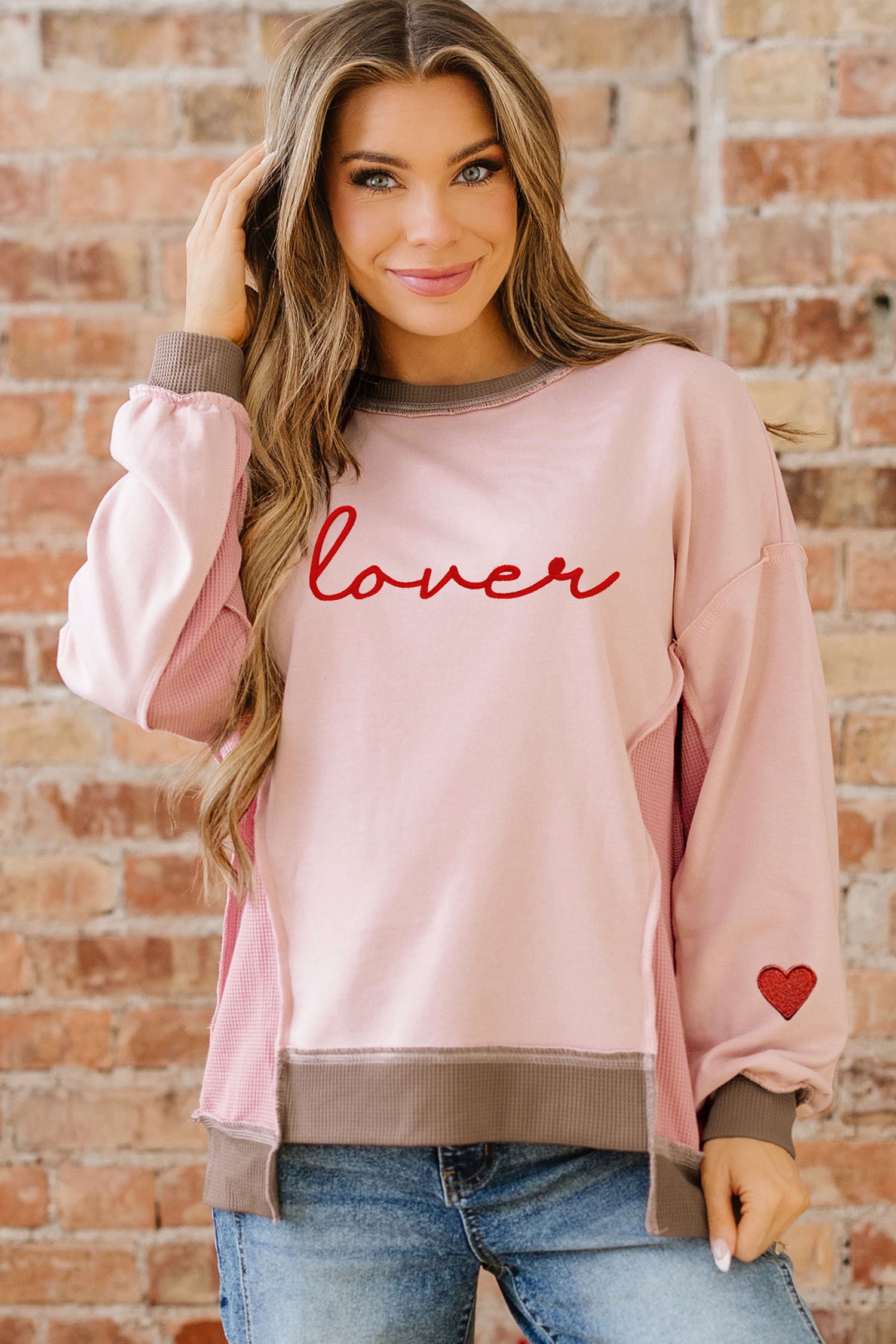 Sweat-shirt rose clair à empiècements gaufrés et broderies, idéal pour les amoureux des sweats à capuche.