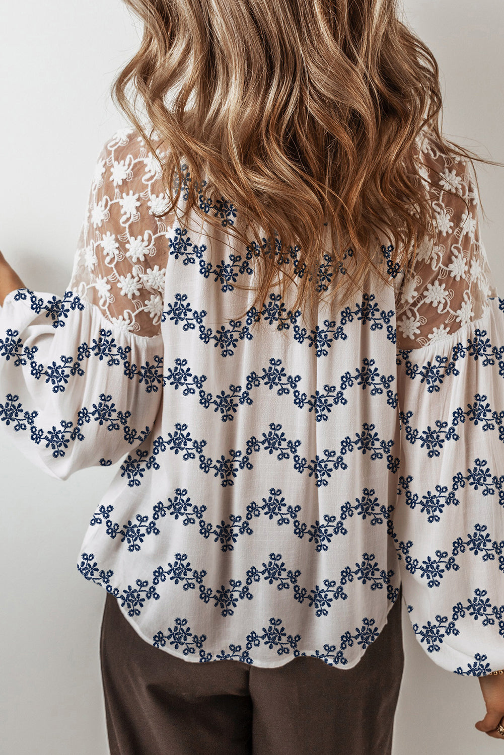 Blouse bleue en dentelle patchwork à motifs floraux, manches bouffantes et col V fendu, style patchwork à manches bouffantes.