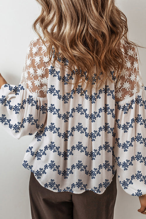 Blouse bleue en dentelle patchwork à motifs floraux, manches bouffantes et col V fendu, style patchwork à manches bouffantes.