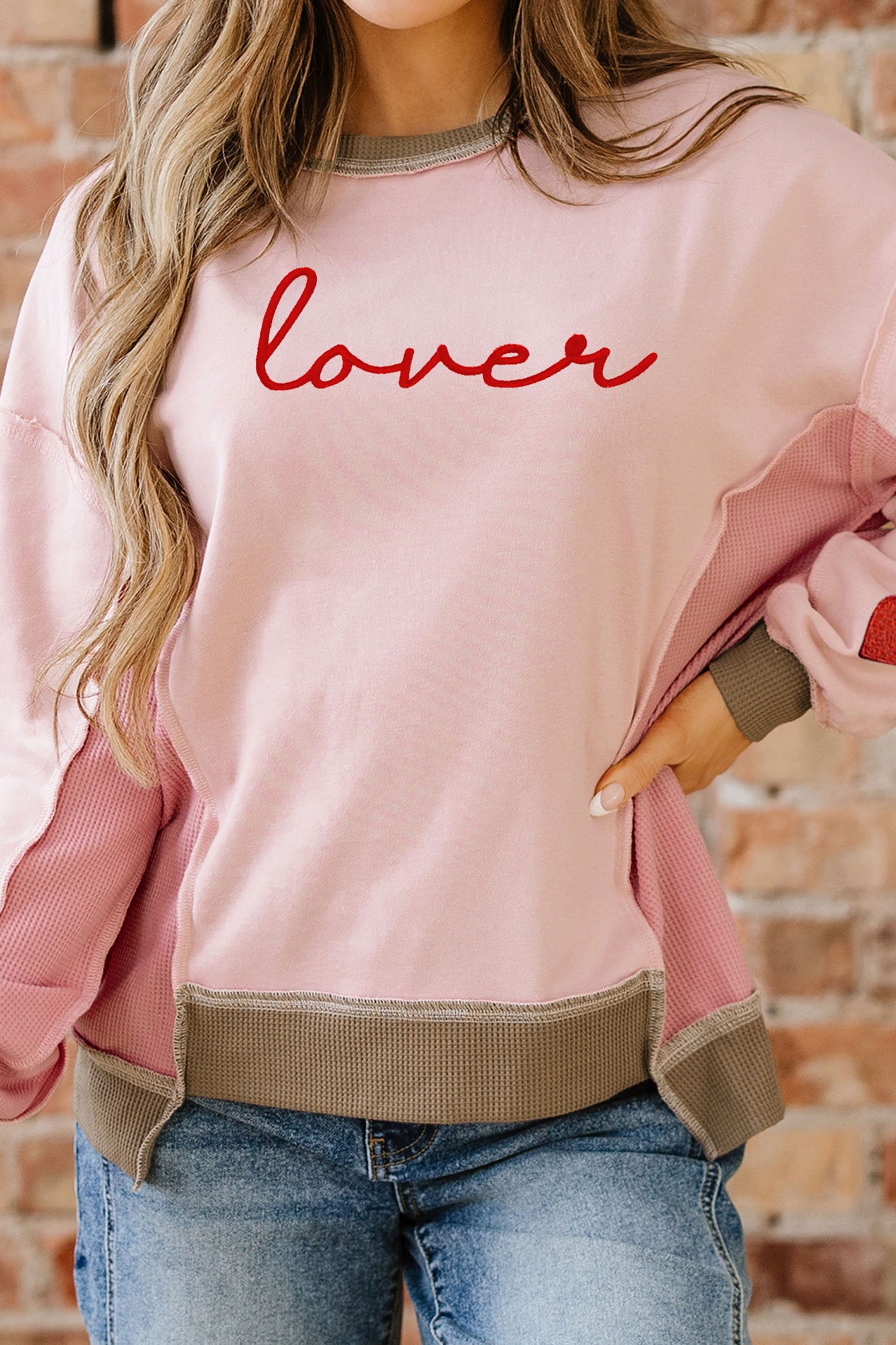Sweat-shirt rose clair à empiècements gaufrés et broderies, idéal pour les amoureux des sweats à capuche.