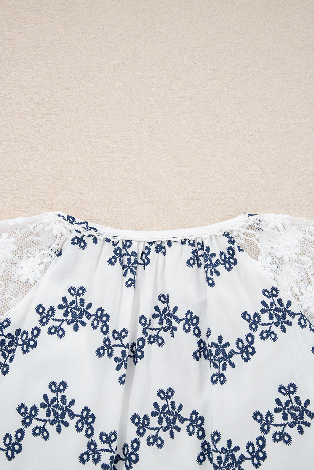 Blouse bleue en dentelle patchwork à motifs floraux, manches bouffantes et col V fendu, style patchwork à manches bouffantes.