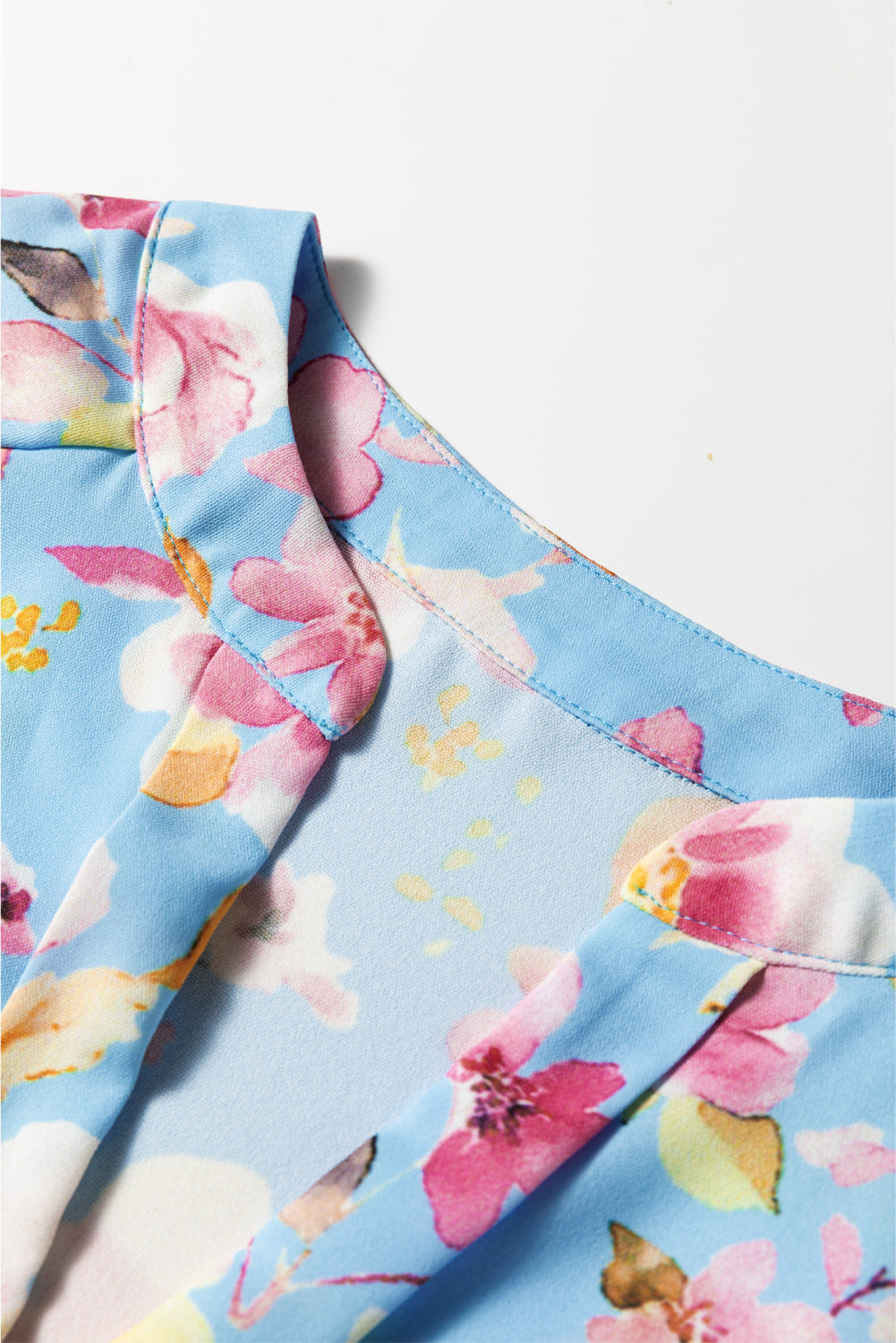 Chemisier bleu ciel à fleurs, poignets froncés, manches volantées, col en V