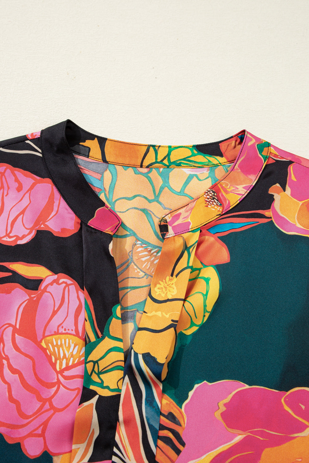 Blusa negra con estampado floral, puños fruncidos, mangas abullonadas y escote en V