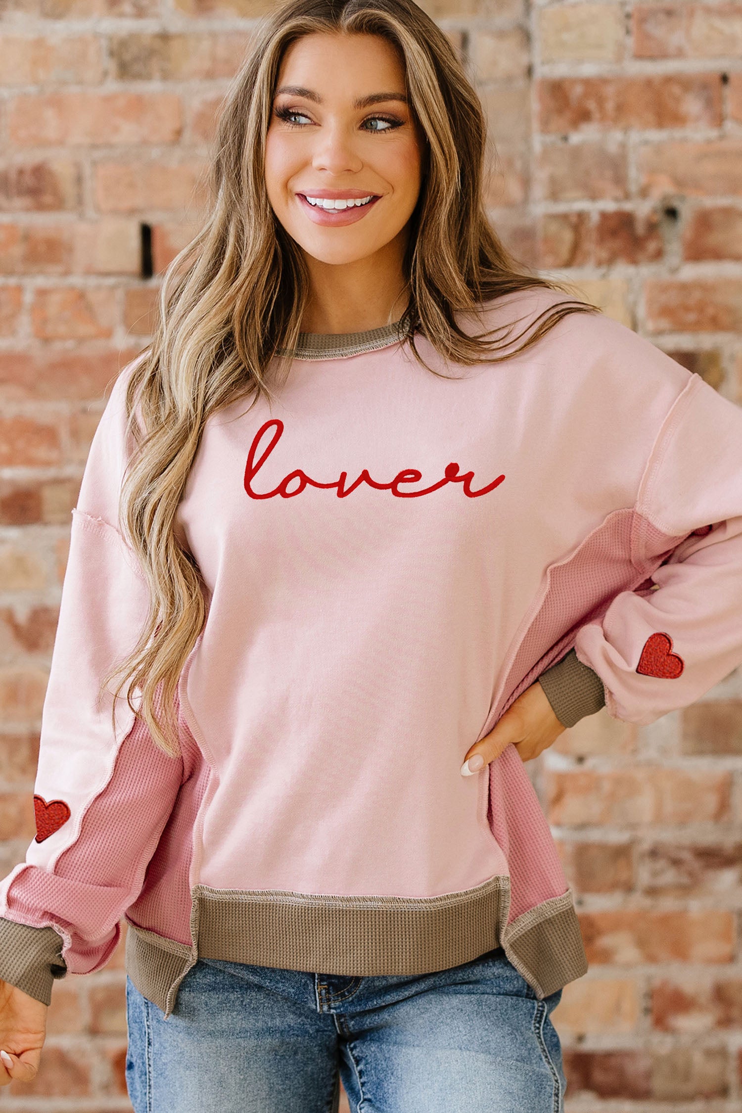 Sweat-shirt rose clair à empiècements gaufrés et broderies, idéal pour les amoureux des sweats à capuche.