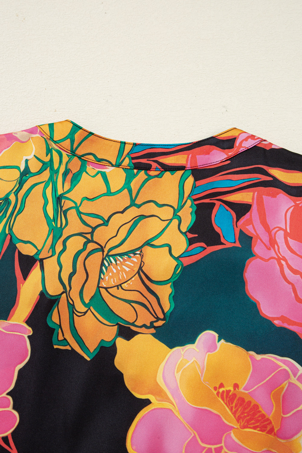 Blusa negra con estampado floral, puños fruncidos, mangas abullonadas y escote en V