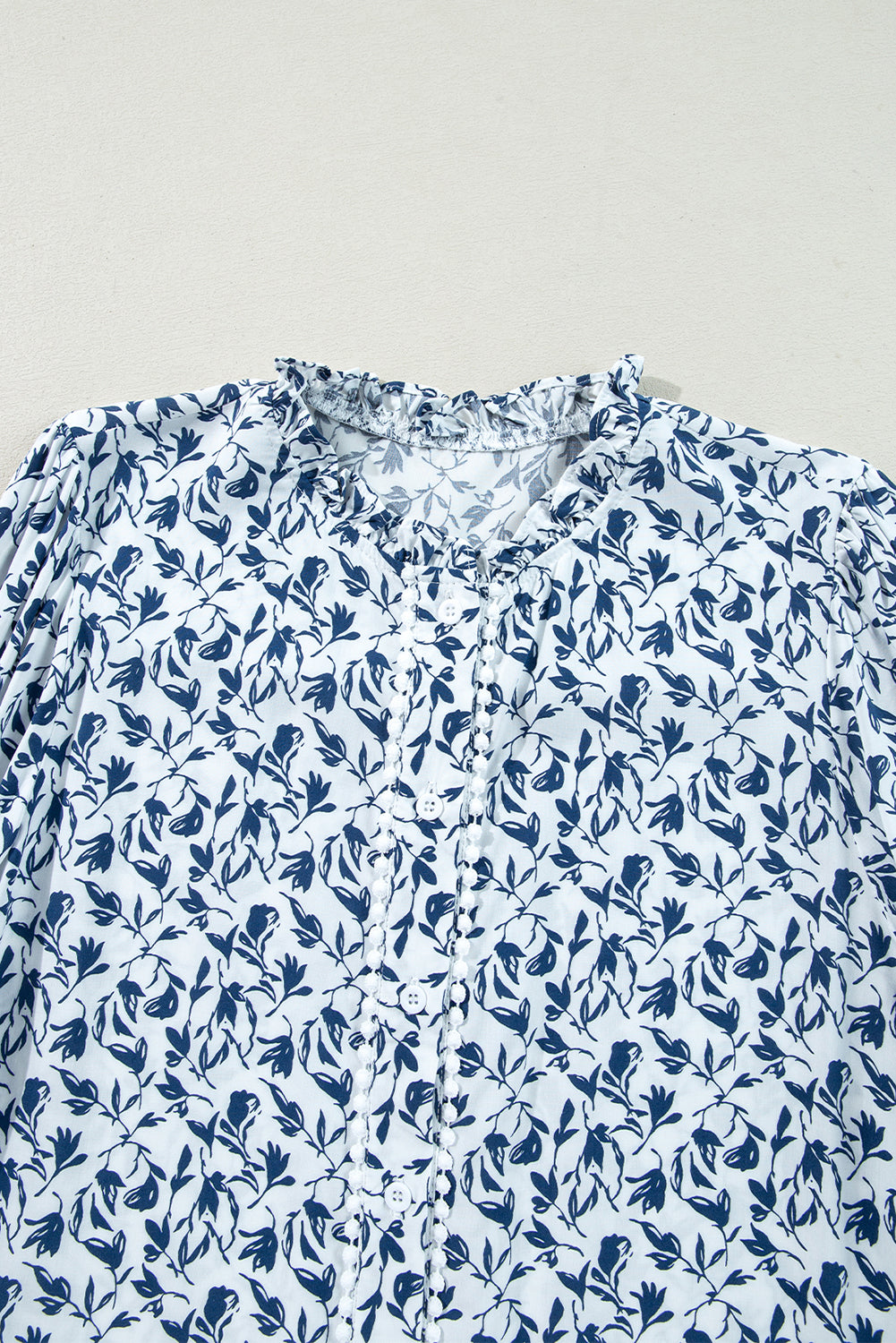 Camisa de otoño con mangas abullonadas, detalle de encaje y estampado floral azul