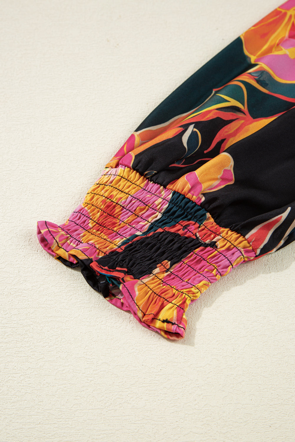 Blusa negra con estampado floral, puños fruncidos, mangas abullonadas y escote en V