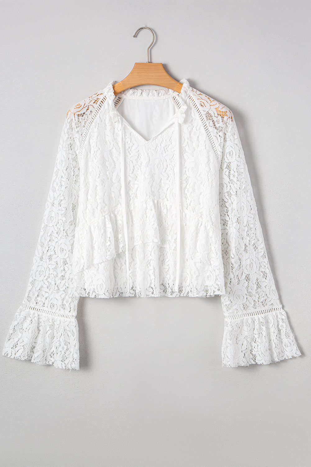Blusa blanca de manga larga con escote en V, detalle de encaje y volantes, cuello en V y lazo.