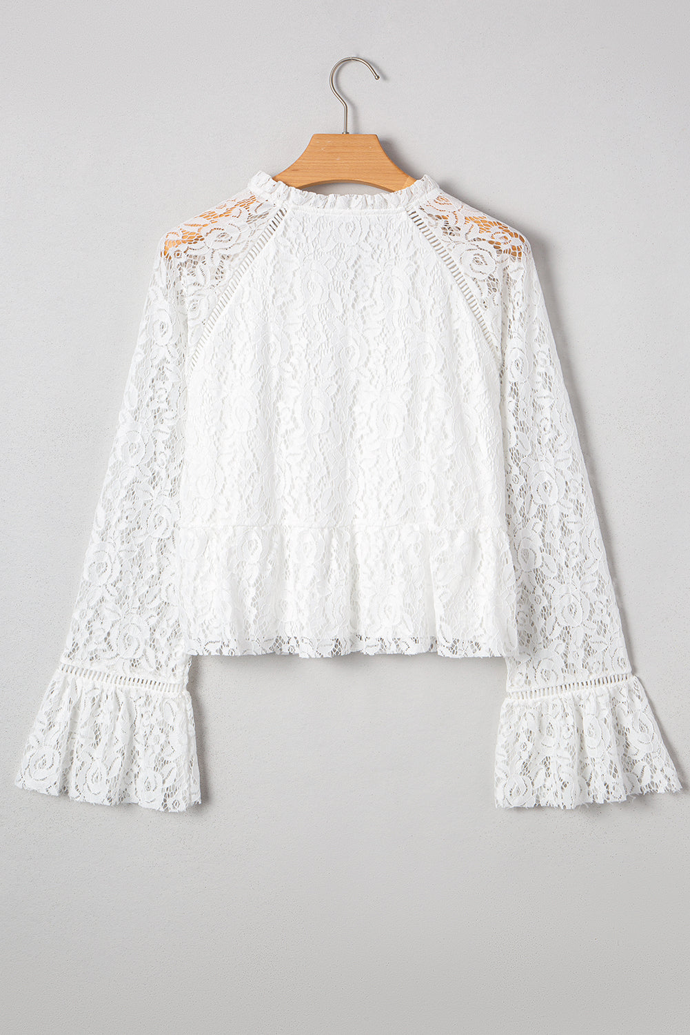 Blusa blanca de manga larga con escote en V, detalle de encaje y volantes, cuello en V y lazo.