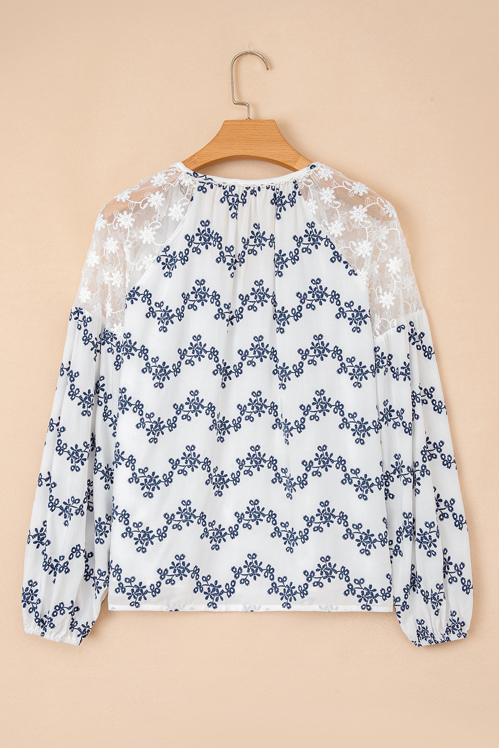 Blouse bleue en dentelle patchwork à motifs floraux, manches bouffantes et col V fendu, style patchwork à manches bouffantes.