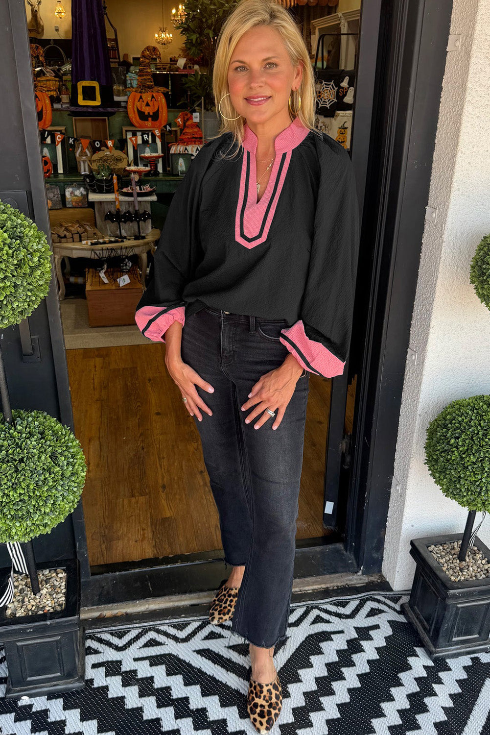 Chemisier noir à manches longues et col en V contrasté.