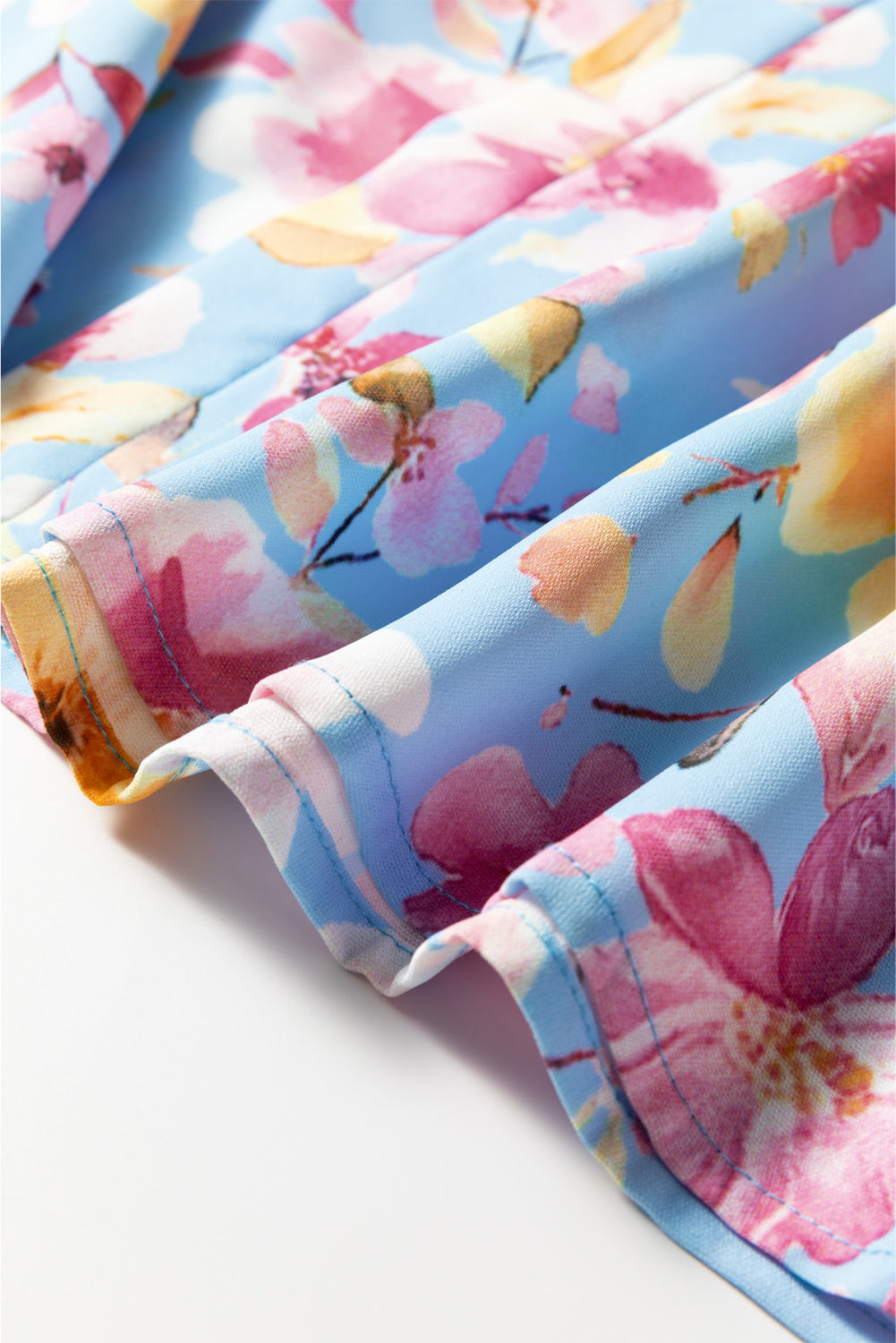 Chemisier bleu ciel à fleurs, poignets froncés, manches volantées, col en V