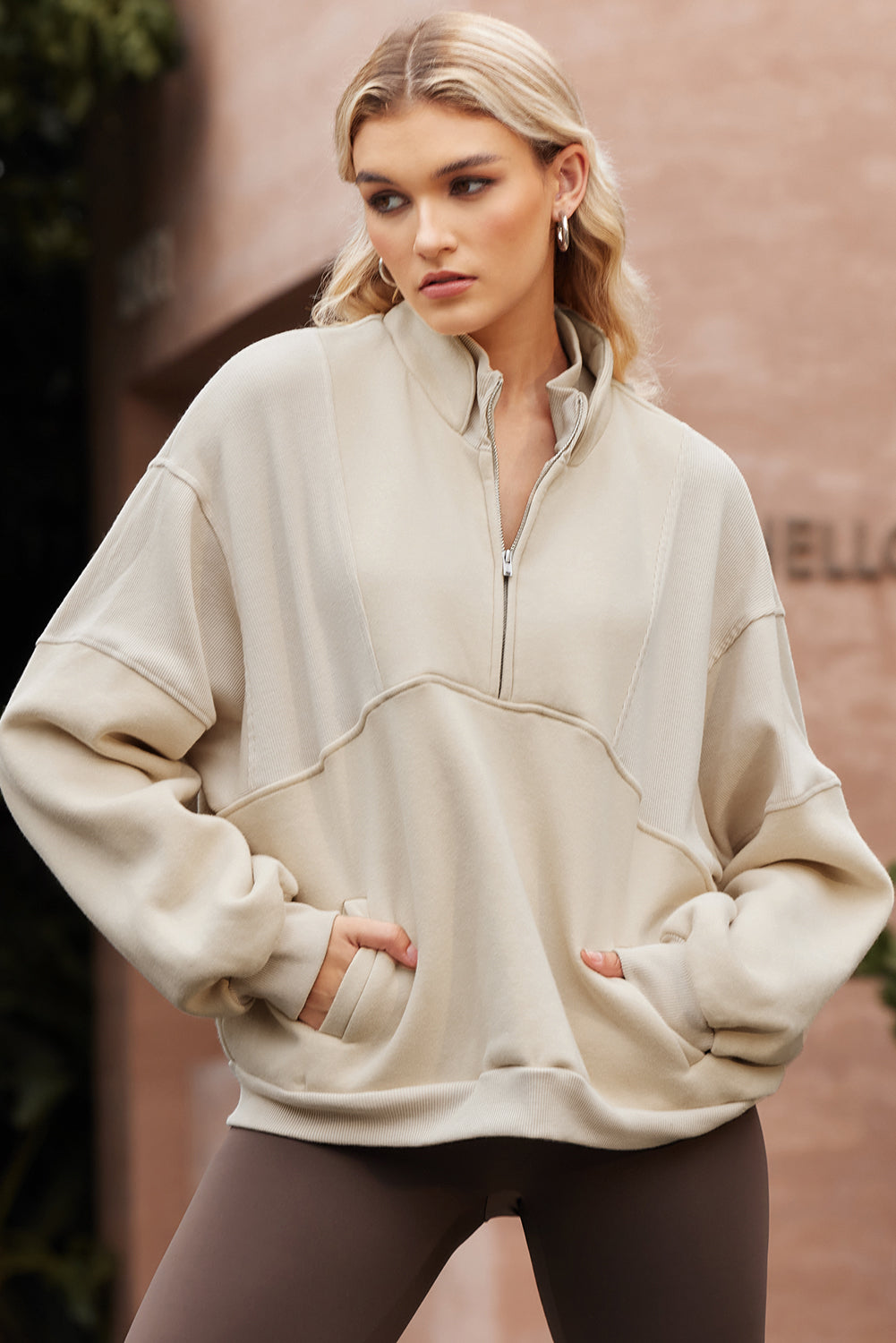 Sudadera informal de color albaricoque con media cremallera, cuello alto y costuras expuestas.