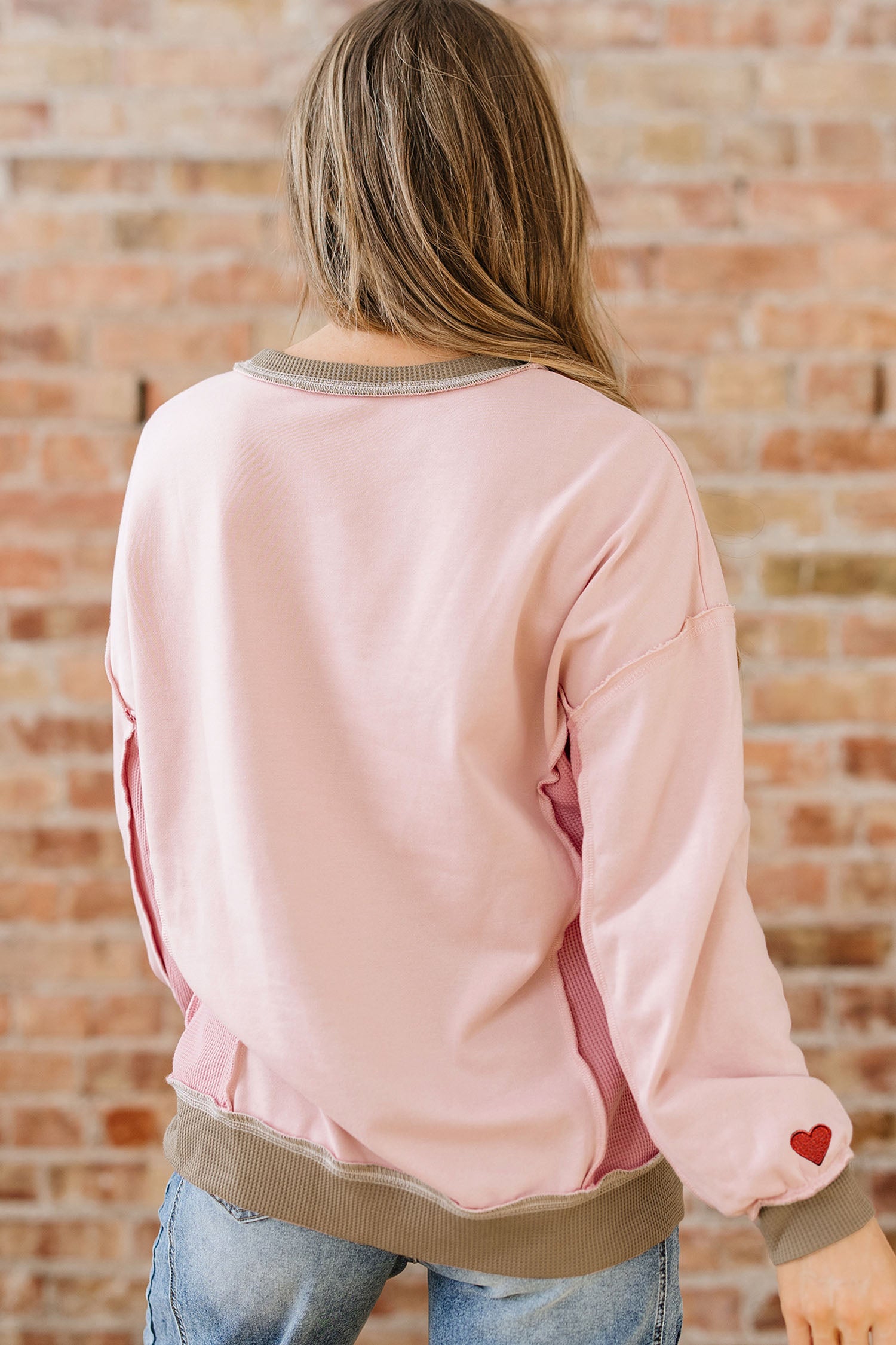 Sweat-shirt rose clair à empiècements gaufrés et broderies, idéal pour les amoureux des sweats à capuche.